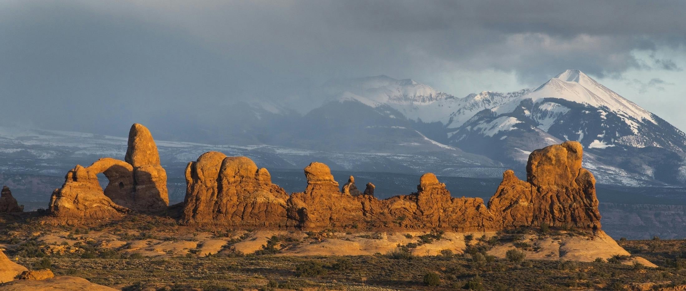 View of red rock formations in Moab National Park with snow-capped mountains – representing Hunghee Energy’s Utah roots and outdoor adventure lifestyle