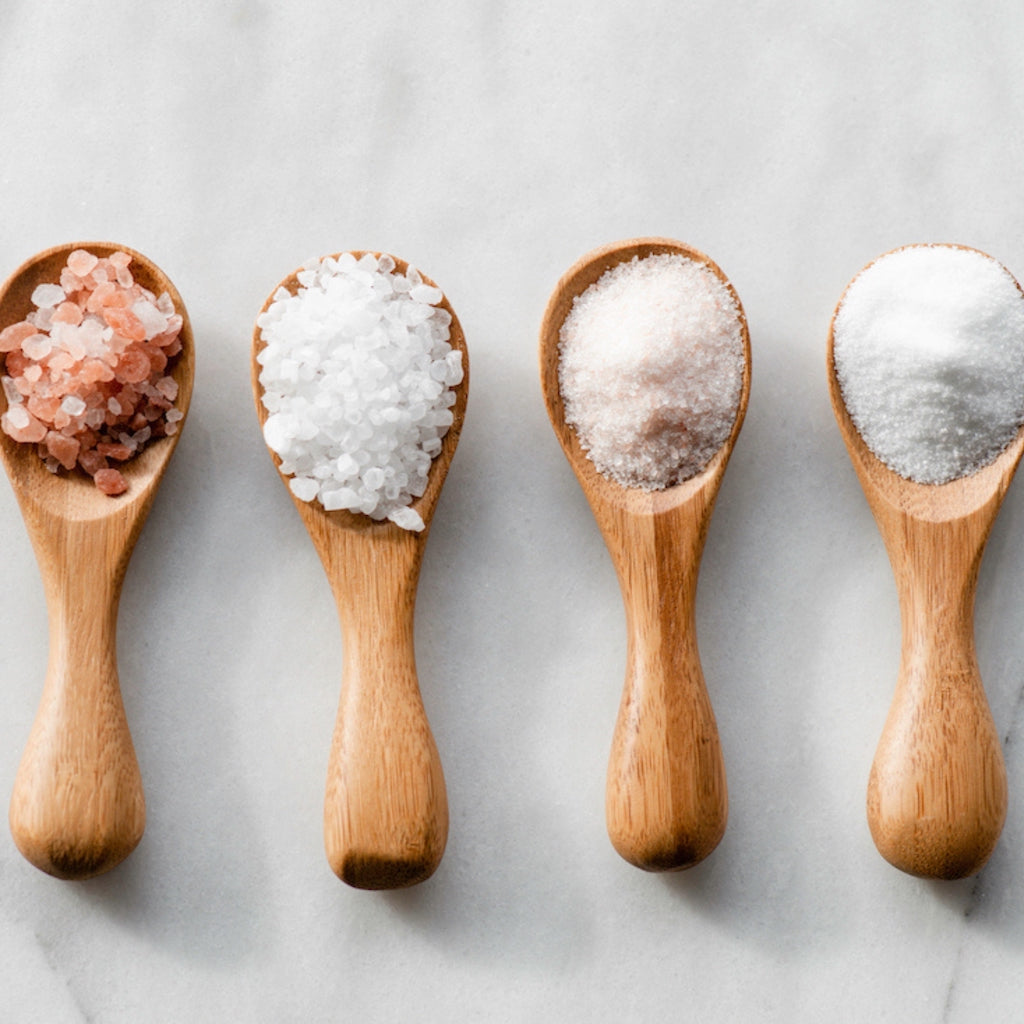 Four wooden spoons filled with different natural sea salts – rich in electrolytes and trace minerals for hydration and muscle recovery