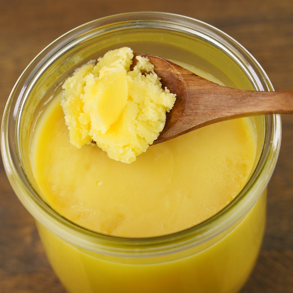 Spoon scooping organic grass-fed ghee from a jar – rich in omega-3 healthy fats that support digestion, endurance, and anti-inflammatory health