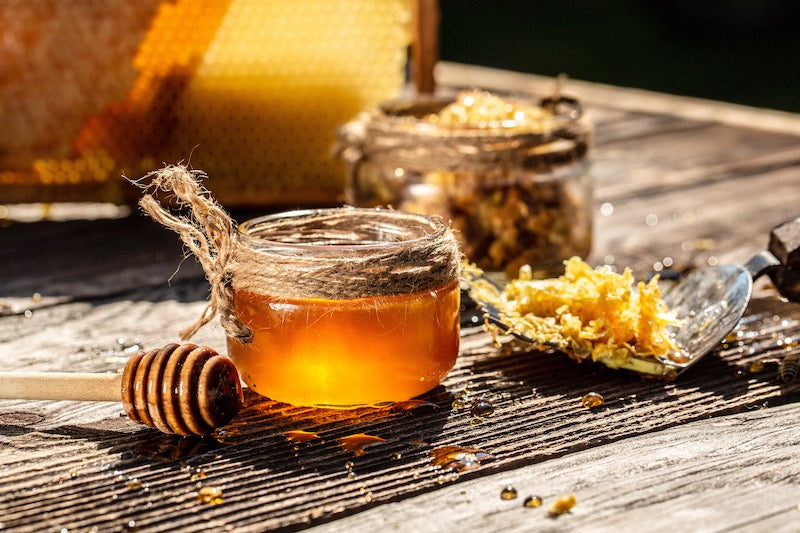 Jar of raw honey with honey dipper and comb on wooden table – natural raw honey used in Hunghee Energy for clean fuel and immunity