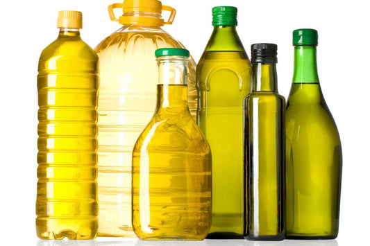 Assorted bottles of cooking oil lined up on a white background, seed oils