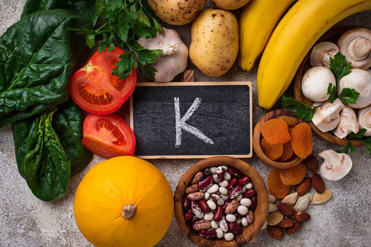 Potassium-rich foods like bananas, spinach, beans and tomatoes around a “K” board, potassium