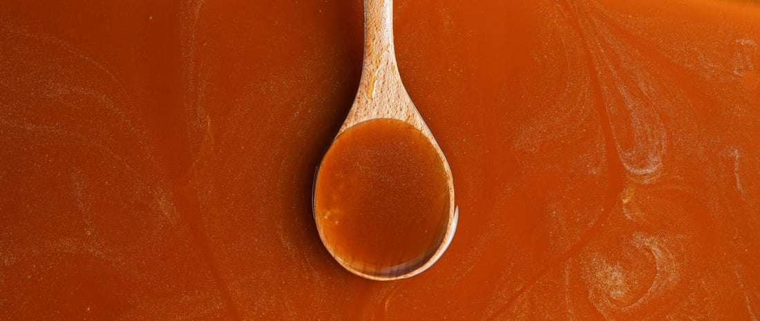 Close-up of raw honey dripping off a wooden spoon, golden and glossy