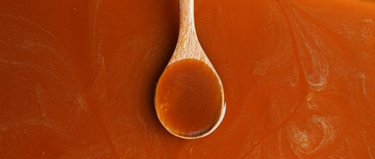 Close-up of raw honey dripping off a wooden spoon, golden and glossy