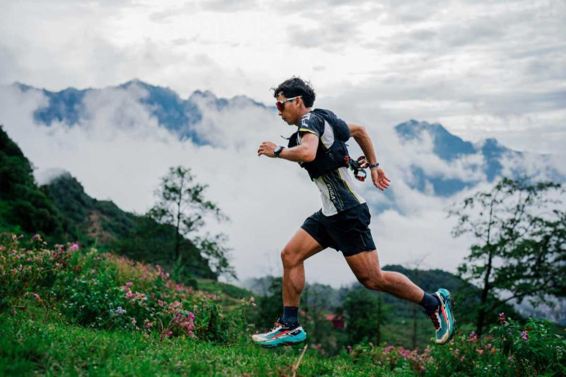 Trail runner charging uphill on a mountain path above clouds, trail running