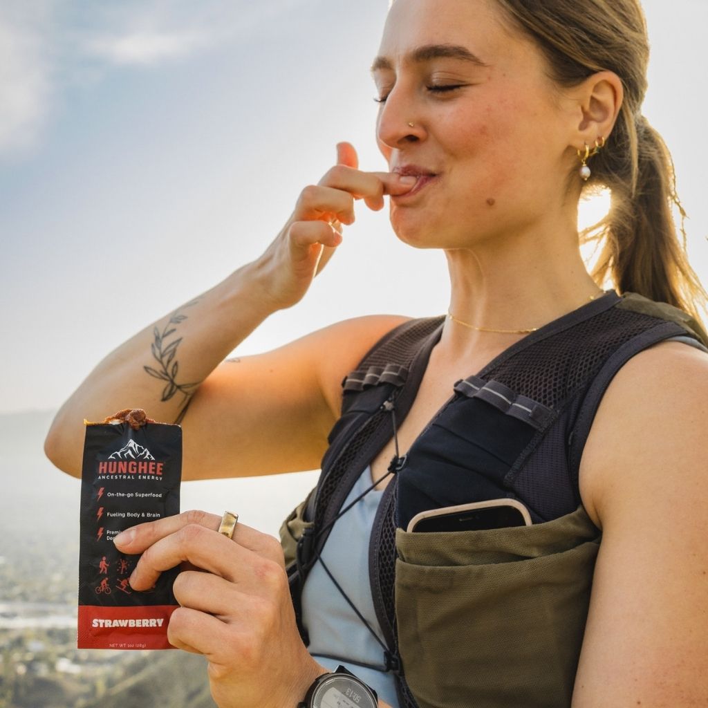 Female hiker eating Hunghee Energy pack – animal-based fuel for trail running, ultras, and endurance athletes