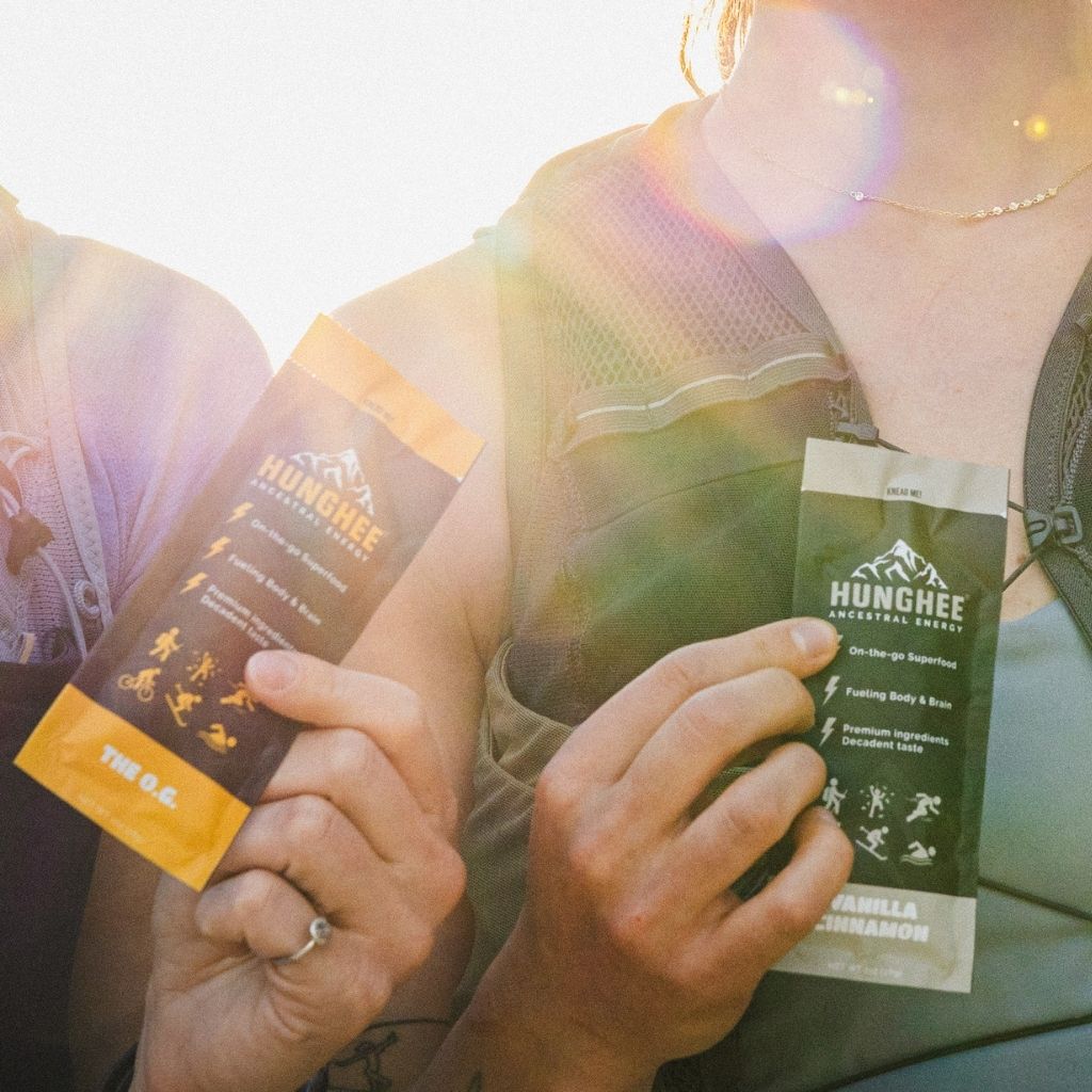 Hikers holding animal-based keto fuel packs with ghee and honey in sunlit trail