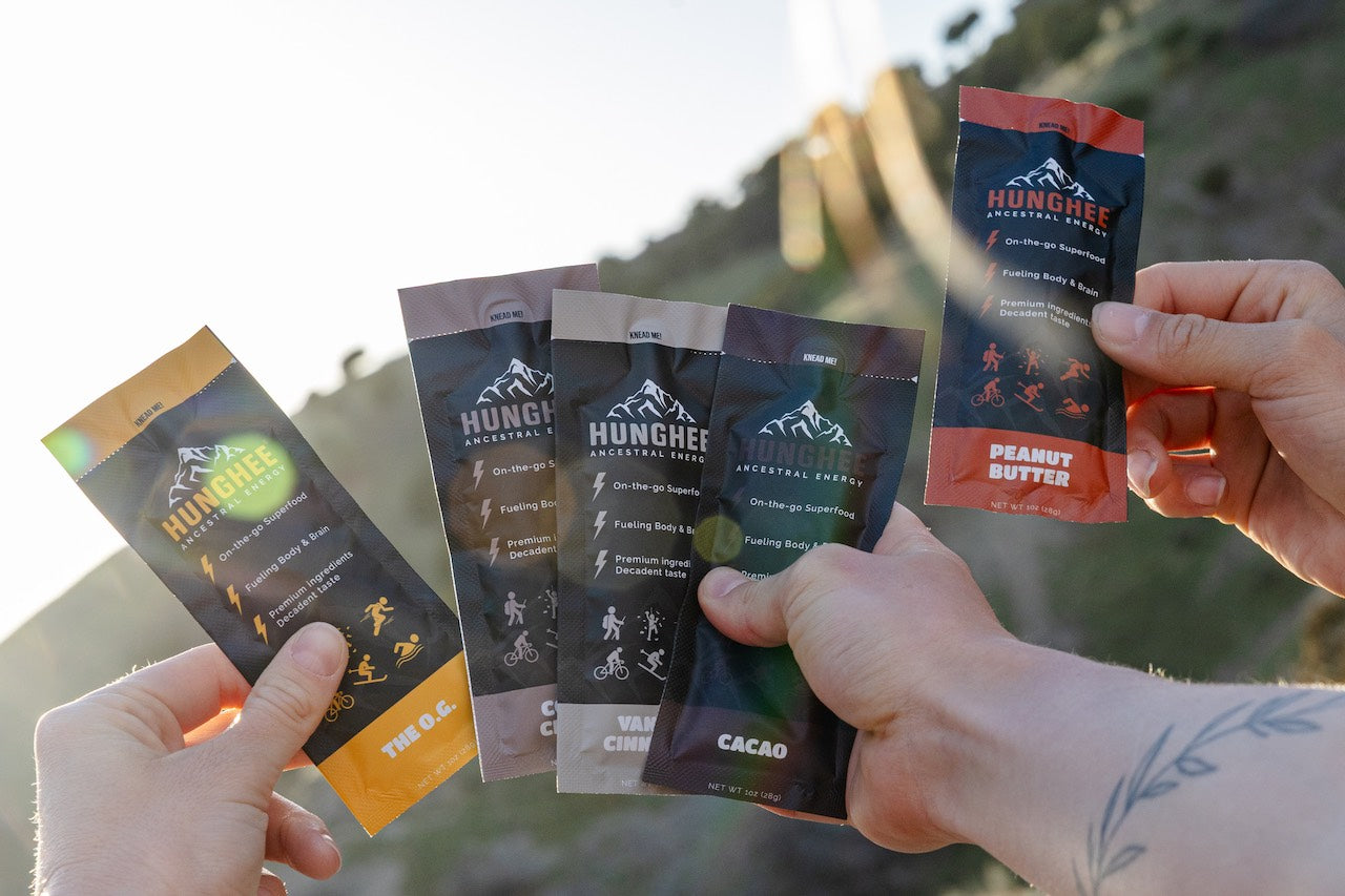 Hands holding Hunghee Energy packs outdoors – animal-based carnivore snack made with raw honey, ghee, and sea salt for athletes